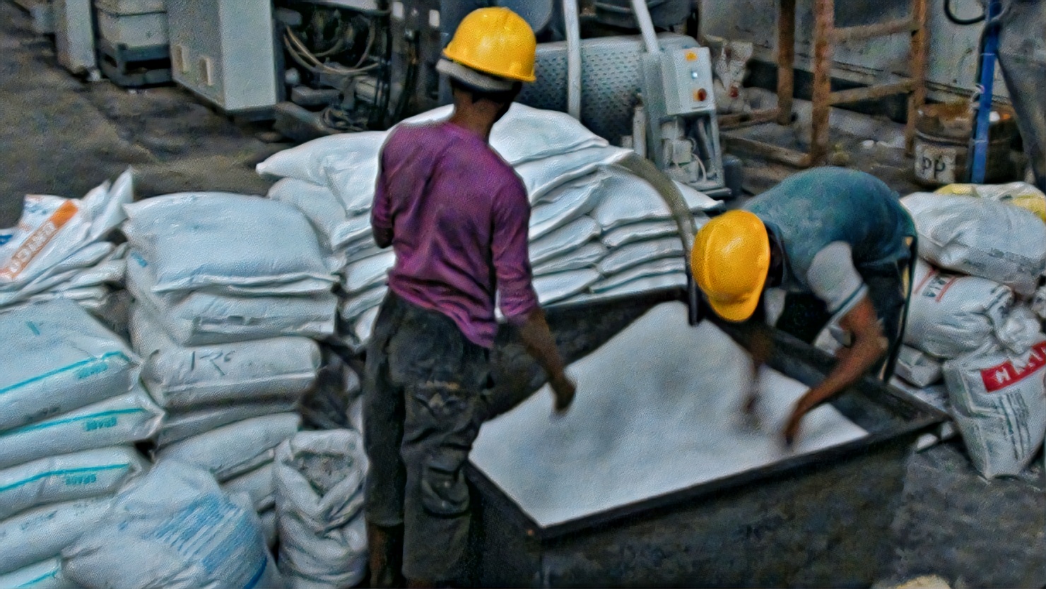 Workers checking fabric beside filled sacks